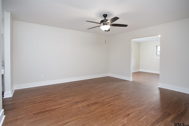 unfurnished room with baseboards, ceiling fan, and dark wood-style floors