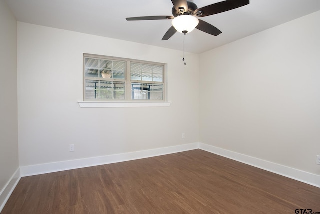spare room featuring baseboards, a ceiling fan, and dark wood finished floors