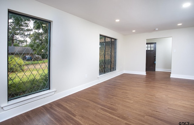 unfurnished room with plenty of natural light, recessed lighting, baseboards, and wood finished floors