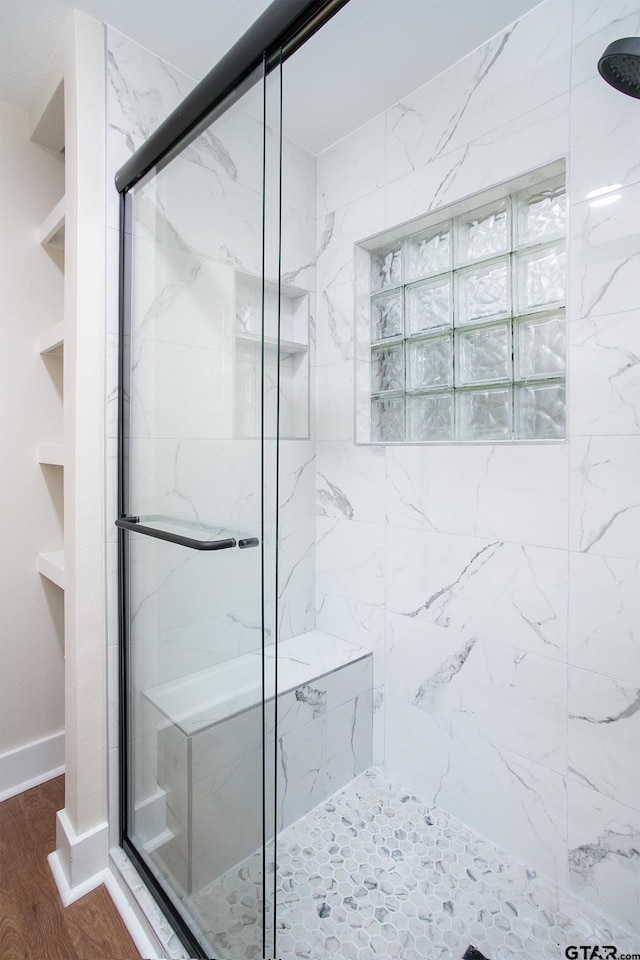full bath with baseboards, a marble finish shower, and wood finished floors