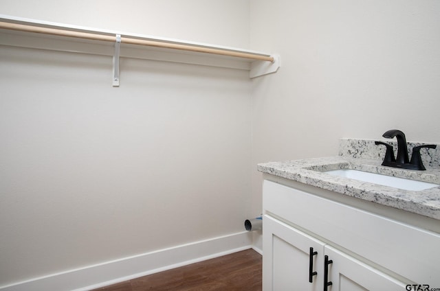 laundry area featuring baseboards, a sink, and dark wood-style flooring