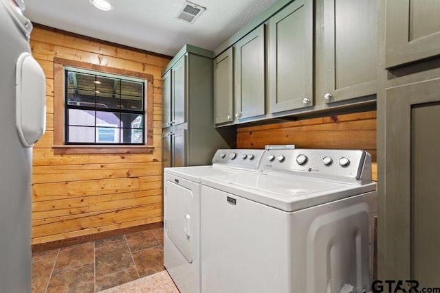 16887 Rainbow Ridge Cir, Tyler, TX 75707 - washroom featuring washing machine and clothes dryer, wood walls, cabinet space, and dark stone finish floors