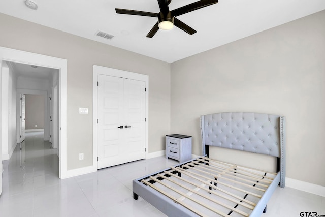 tiled bedroom with ceiling fan and a closet