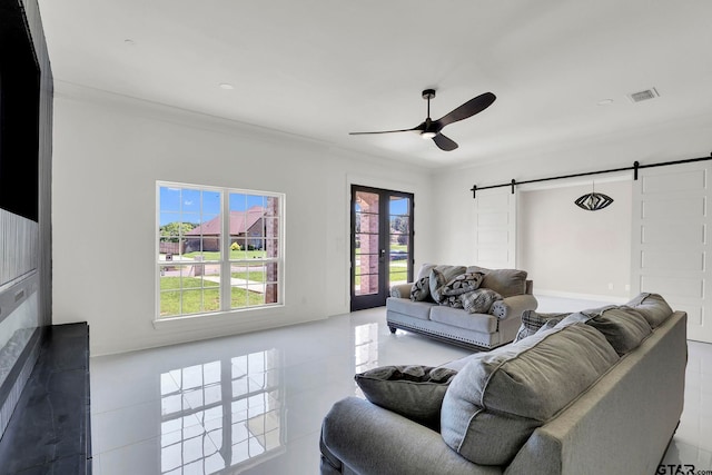 living room with ceiling fan, a barn door, crown molding, and french doors