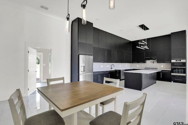 kitchen featuring crown molding, decorative light fixtures, decorative backsplash, a kitchen island, and appliances with stainless steel finishes