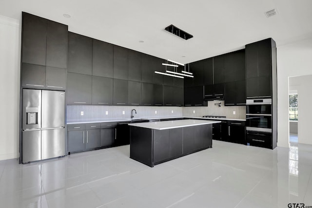 kitchen with sink, decorative backsplash, light tile patterned floors, appliances with stainless steel finishes, and a kitchen island