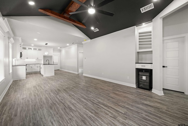 unfurnished living room featuring high vaulted ceiling, dark wood-type flooring, sink, and beam ceiling