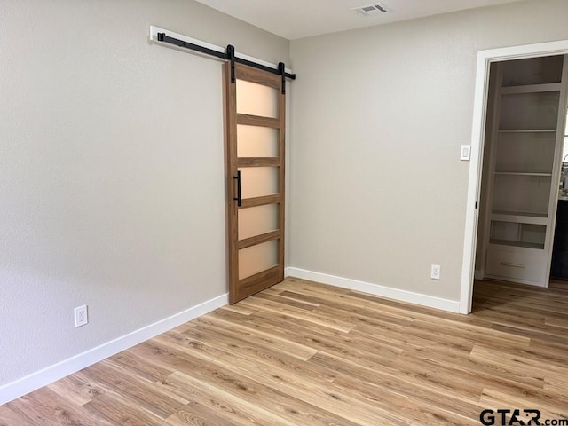 1113 Swanson Dr, Palestine, TX 75801 - unfurnished room featuring a barn door, light wood finished floors, and baseboards