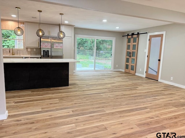 1113 Swanson Dr, Palestine, TX 75801 - kitchen featuring stainless steel fridge with ice dispenser, light countertops, a barn door, light wood-type flooring, and tasteful backsplash