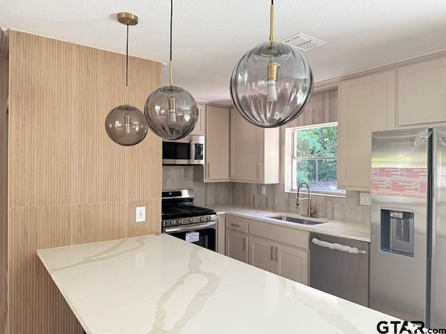 1113 Swanson Dr, Palestine, TX 75801 - kitchen featuring stainless steel appliances, a sink, light stone counters, decorative backsplash, and decorative light fixtures