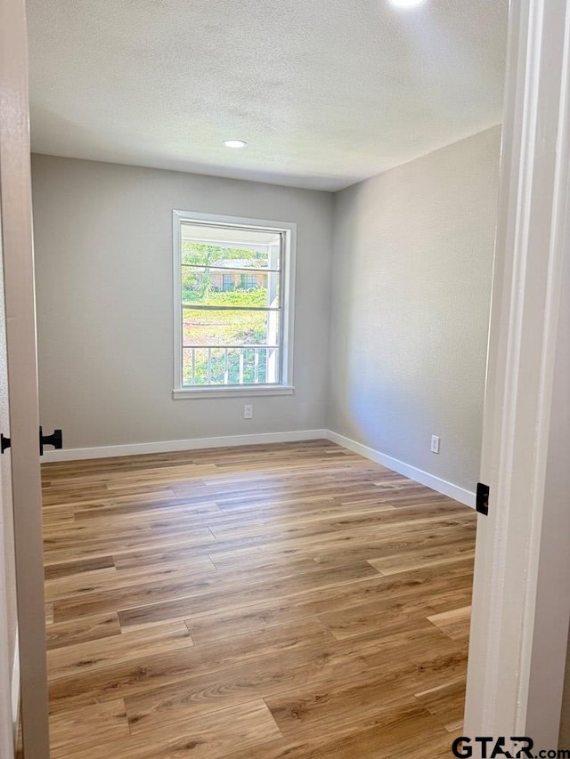 1113 Swanson Dr, Palestine, TX 75801 - spare room featuring light wood-style flooring, baseboards, and a textured ceiling
