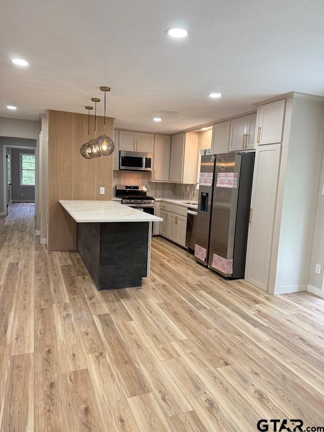 1113 Swanson Dr, Palestine, TX 75801 - kitchen featuring appliances with stainless steel finishes, light countertops, a peninsula, light wood-style floors, and backsplash