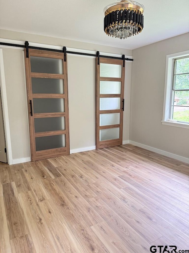 1113 Swanson Dr, Palestine, TX 75801 - unfurnished room featuring a barn door, light wood-type flooring, and baseboards