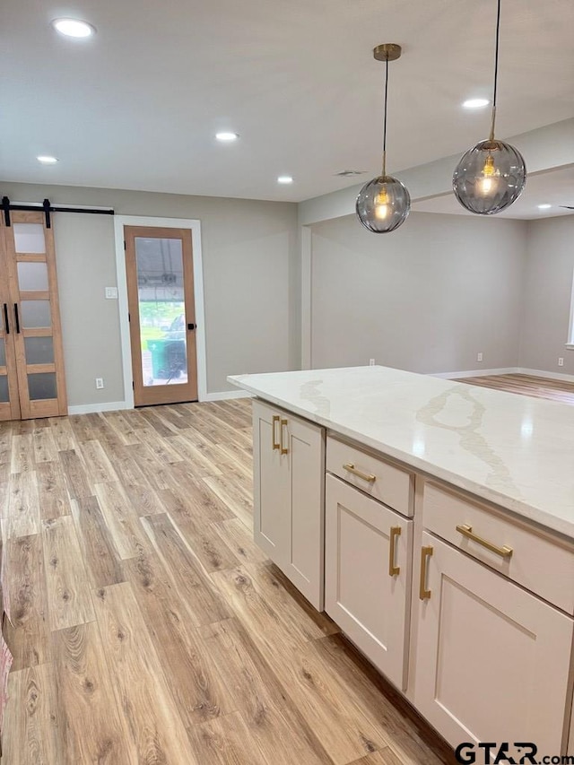 1113 Swanson Dr, Palestine, TX 75801 - kitchen featuring a barn door, light wood-style flooring, pendant lighting, light stone countertops, and recessed lighting