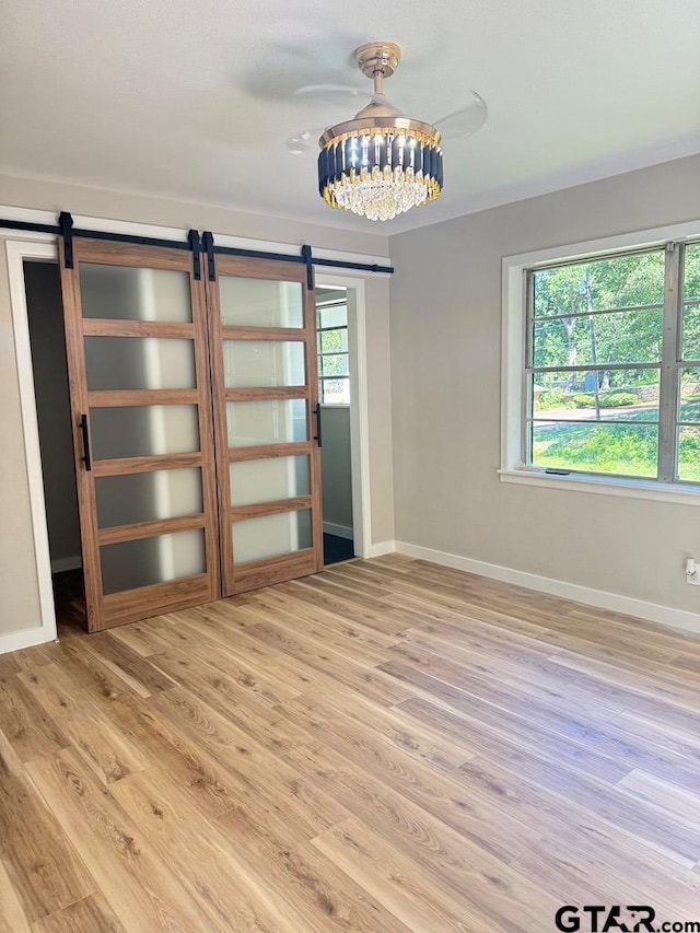 1113 Swanson Dr, Palestine, TX 75801 - spare room featuring a barn door, healthy amount of natural light, and light wood-style flooring
