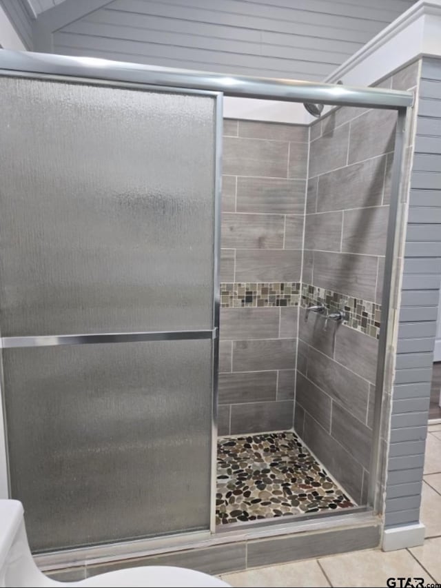 bathroom featuring tile patterned flooring, an enclosed shower, and toilet