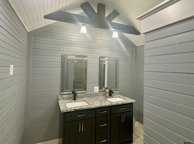 bathroom with tile patterned flooring, vaulted ceiling, vanity, and wood walls