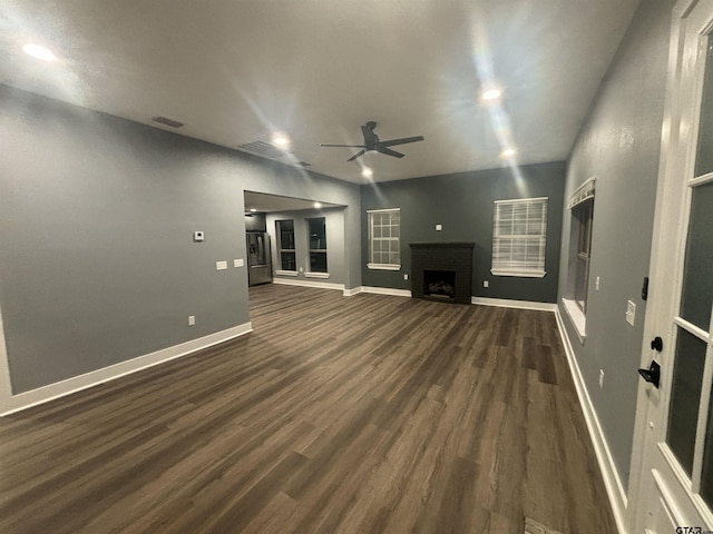 unfurnished living room with a brick fireplace, dark hardwood / wood-style floors, and ceiling fan