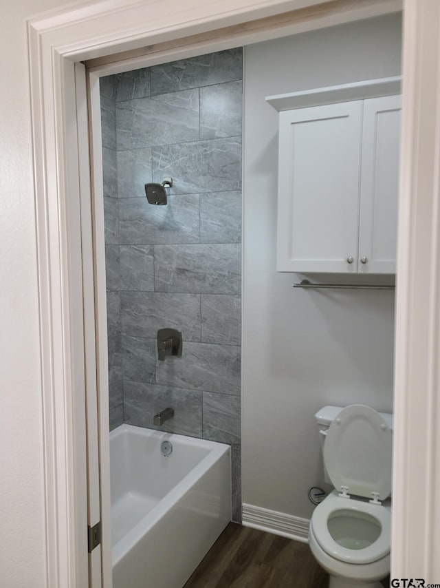 bathroom with hardwood / wood-style floors, tiled shower / bath combo, and toilet