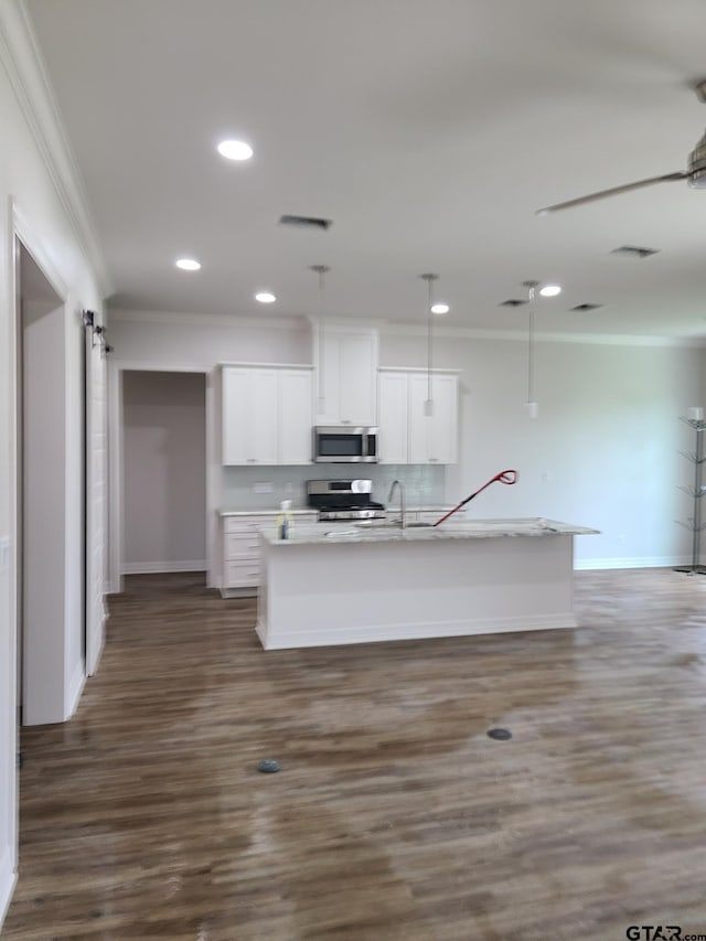 kitchen with stainless steel appliances, dark wood-type flooring, white cabinets, an island with sink, and ornamental molding