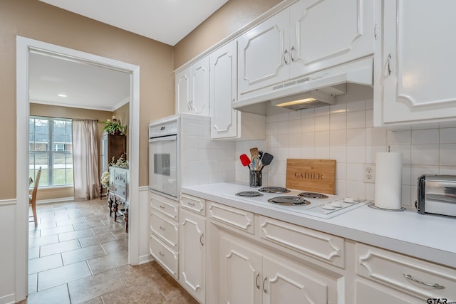 kitchen featuring white appliances, backsplash, ornamental molding, light tile patterned flooring, and white cabinetry