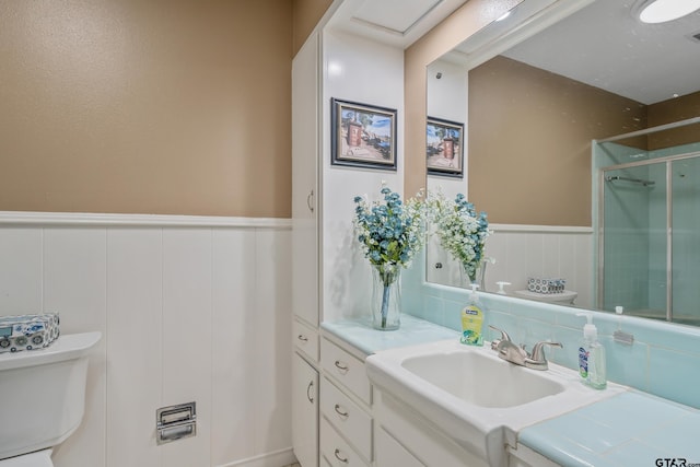 bathroom featuring vanity, toilet, and a shower with shower door