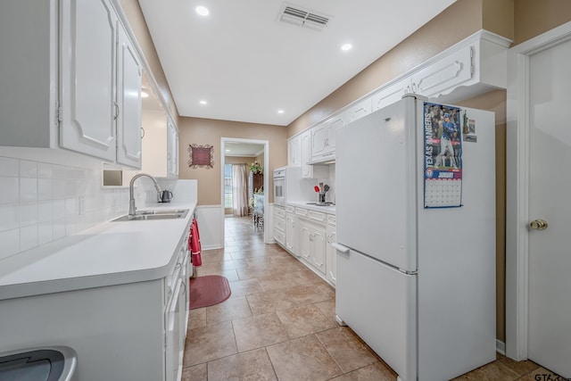 kitchen featuring backsplash, sink, white cabinets, and white appliances