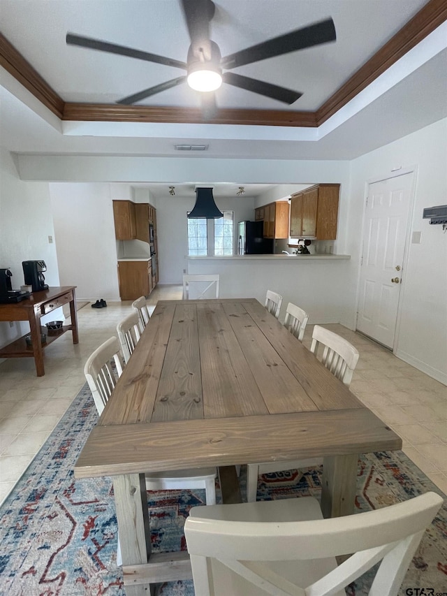 dining space featuring ceiling fan, ornamental molding, and a tray ceiling