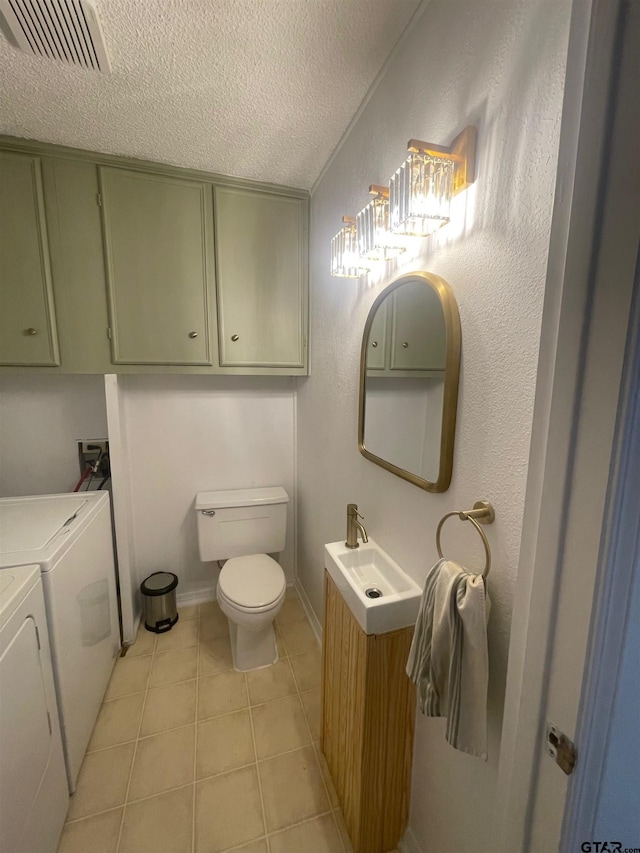 bathroom featuring tile patterned flooring, vanity, washing machine and clothes dryer, toilet, and a textured ceiling