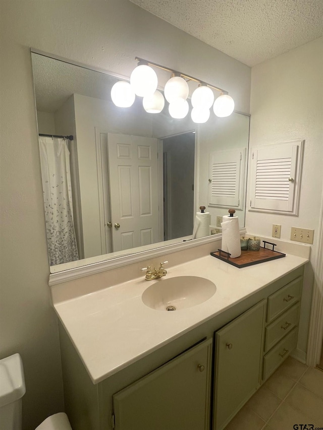 bathroom with tile patterned flooring, vanity, a textured ceiling, and toilet