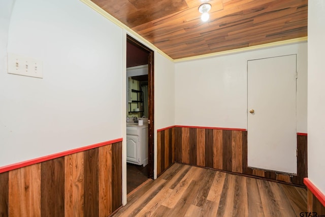 empty room with wooden walls, dark wood finished floors, wooden ceiling, a wainscoted wall, and vaulted ceiling