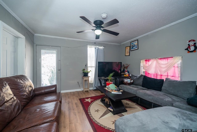 living area with baseboards, ceiling fan, ornamental molding, and wood finished floors