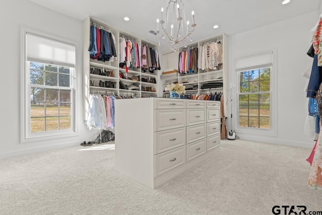 spacious closet with a notable chandelier and light carpet