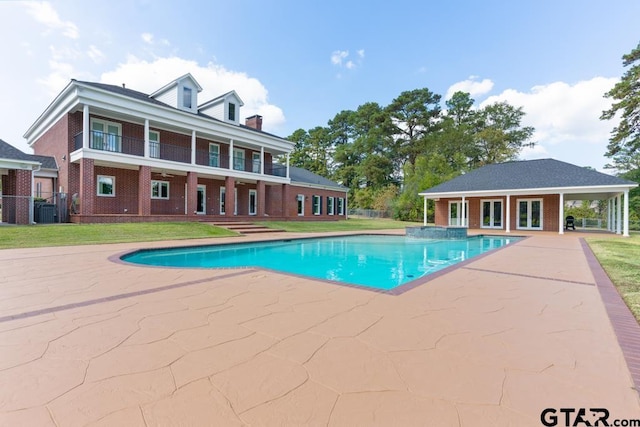 view of pool featuring an outbuilding, cooling unit, a lawn, and a patio area