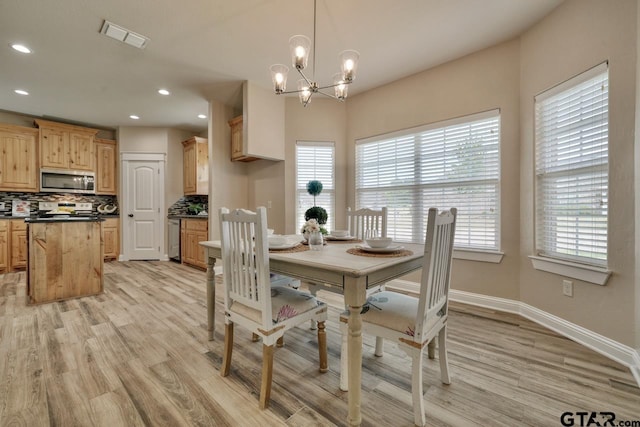 dining space with light wood-type flooring and a notable chandelier