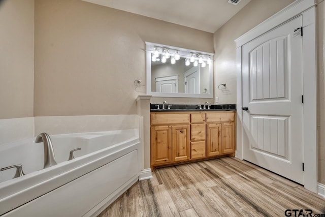 bathroom featuring wood-type flooring, vanity, and a tub