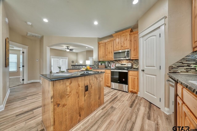 kitchen featuring sink, light wood-type flooring, tasteful backsplash, a kitchen island, and stainless steel appliances