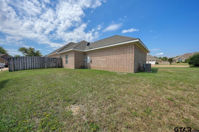 rear view of house with central air condition unit and a lawn