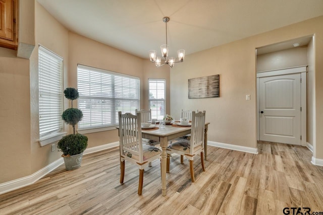 dining space with light hardwood / wood-style floors and an inviting chandelier