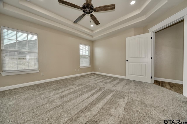 spare room with carpet flooring, ceiling fan, and a tray ceiling