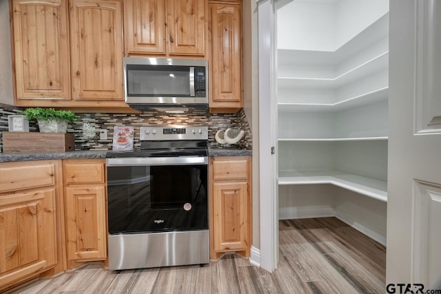 kitchen featuring appliances with stainless steel finishes, backsplash, and light hardwood / wood-style flooring