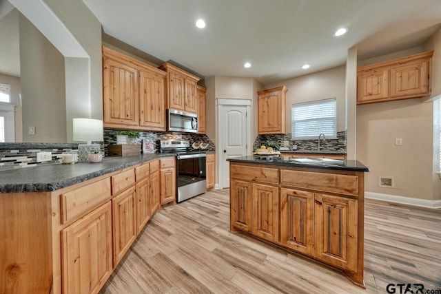 kitchen featuring decorative backsplash, appliances with stainless steel finishes, light hardwood / wood-style flooring, and sink