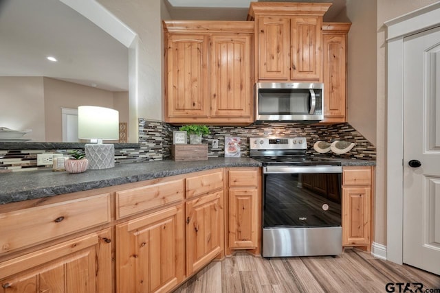 kitchen featuring decorative backsplash, light brown cabinetry, light wood-type flooring, and appliances with stainless steel finishes