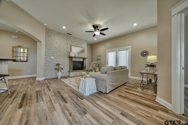 living room with a fireplace, light hardwood / wood-style flooring, and ceiling fan