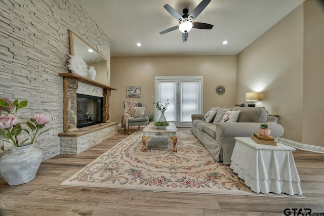 living room with ceiling fan, a fireplace, and light hardwood / wood-style floors