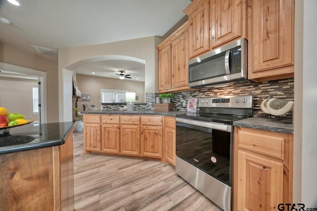 kitchen with appliances with stainless steel finishes, backsplash, light hardwood / wood-style flooring, and plenty of natural light