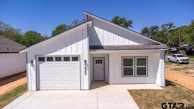 view of front of property with concrete driveway, roof with shingles, board and batten siding, and a garage