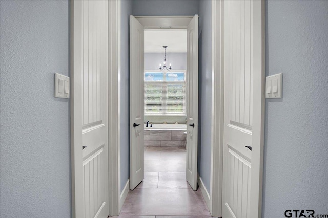 14621 Twin Pine Ln, Lindale, TX 75771 - hallway with a chandelier, light tile patterned flooring, and a textured wall