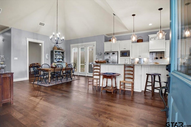 14621 Twin Pine Ln, Lindale, TX 75771 - kitchen featuring stainless steel appliances, white cabinets, a breakfast bar, dark wood-style flooring, and high vaulted ceiling