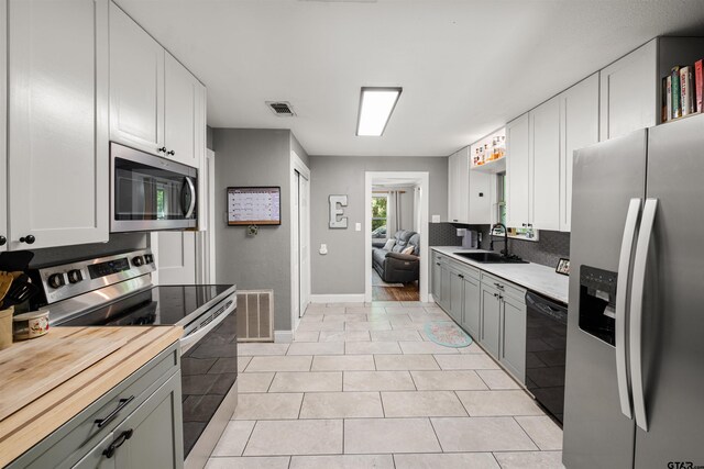 kitchen with white cabinetry, sink, appliances with stainless steel finishes, light tile patterned floors, and gray cabinets